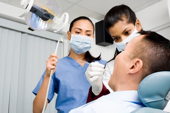 Dental hygienist assisting the dentist as she cleans a patient's teeth