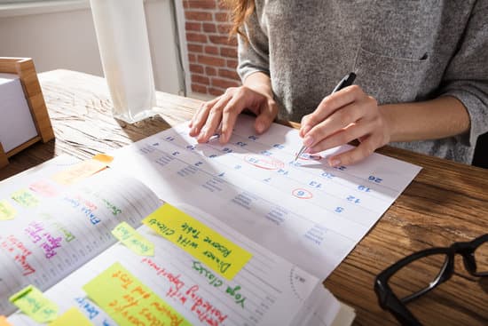 Close-up Of A Student Marking Schedule On Calendar From Diary At Workplace
