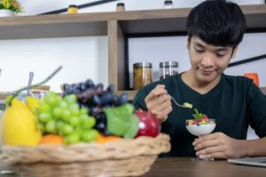 A handsome young Asian man is happy and is eating fruit yoghurt in the modern restaurant. Health care concept