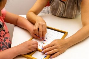 Teacher guiding a student with an educational toy