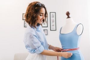 Woman using a tape measure to measure the clothes on a mannequin