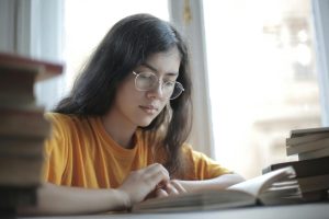 Woman reading one of the books stacked on her table