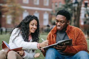 Two college students happily doing homework outside their campus