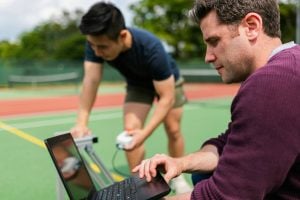 Two students testing out a tennis ball in the tennis court