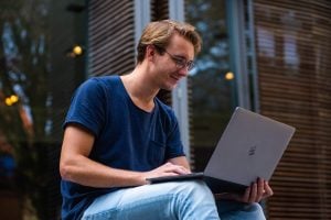 Man sitting down while using his laptop
