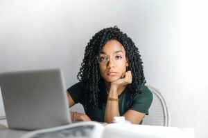Woman looking directly at the camera, while her laptop is on the table