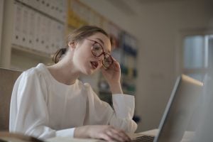 Woman with her hand on her head while looking at her laptop