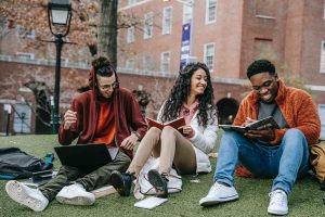 Students sitting on a campus lawn while doing their homework