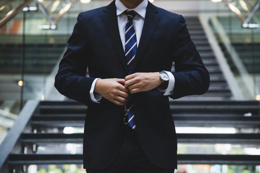 A man in a suit and tie standing confidently on a staircase