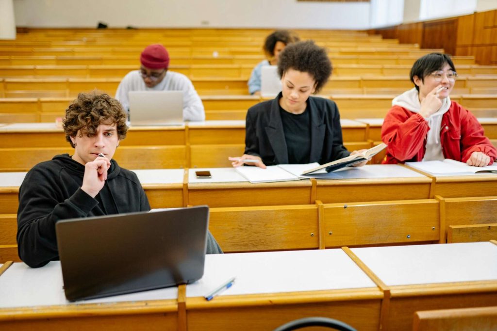 College students with laptops and notebooks are studying inside a classroom