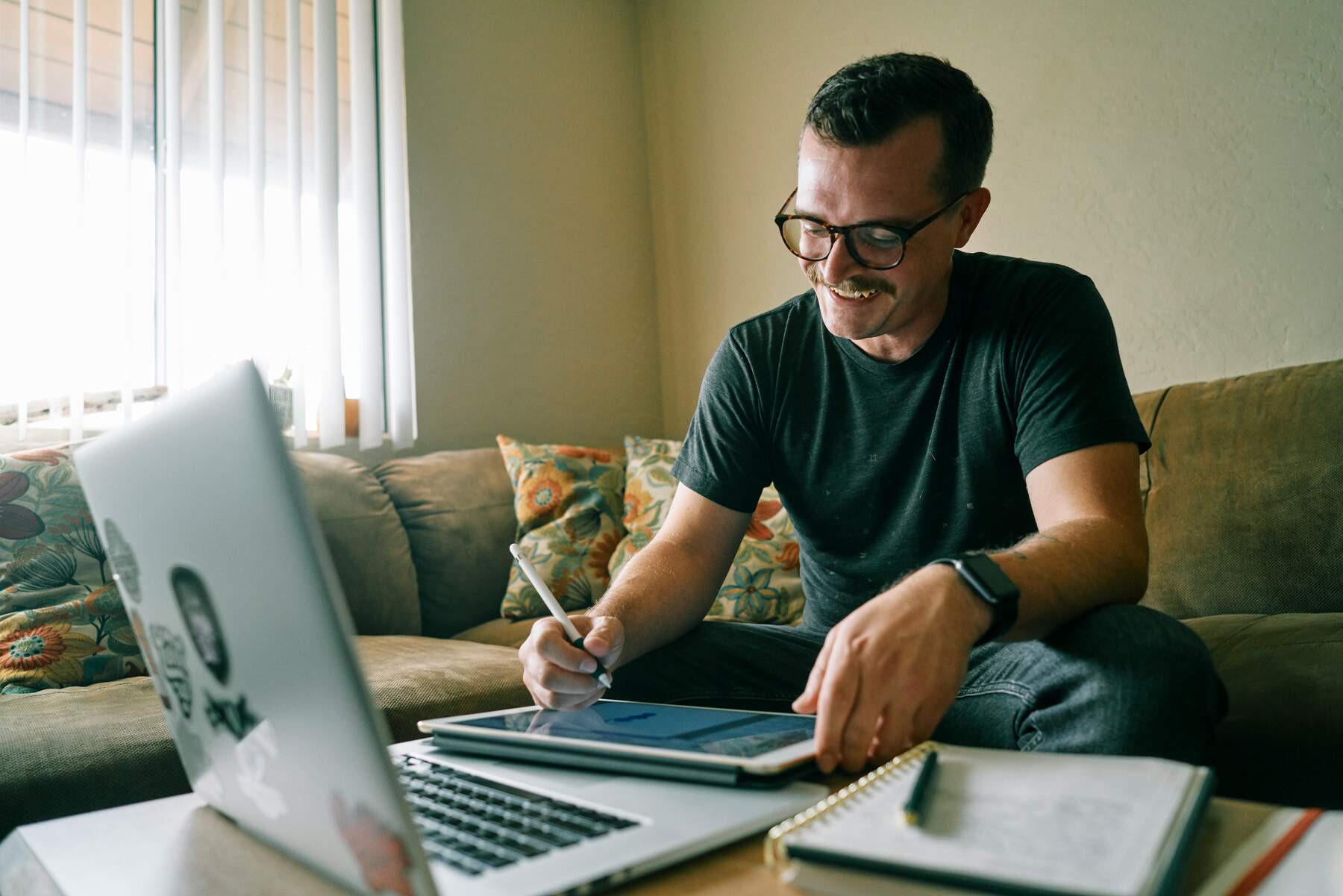 Man using his laptop while writing on a tablet