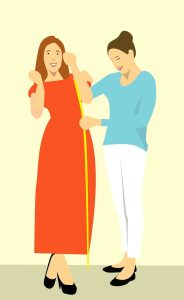 Fashion designer using a tape measure to measure the clothes that a woman is wearing during a fitting