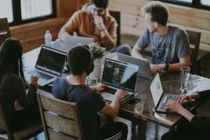 Group of students sitting on a table while all using their laptops