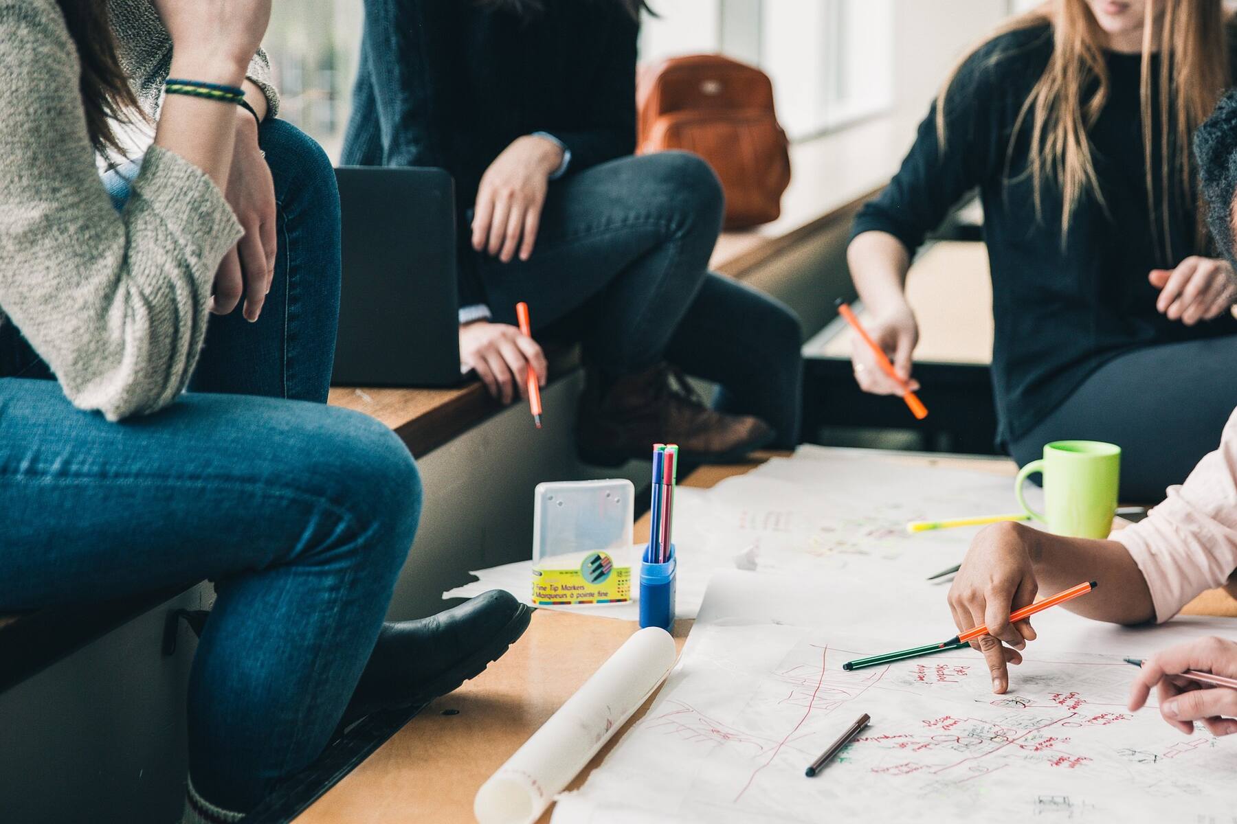 A diverse group of people sitting around a table with a drawing of a new project plan