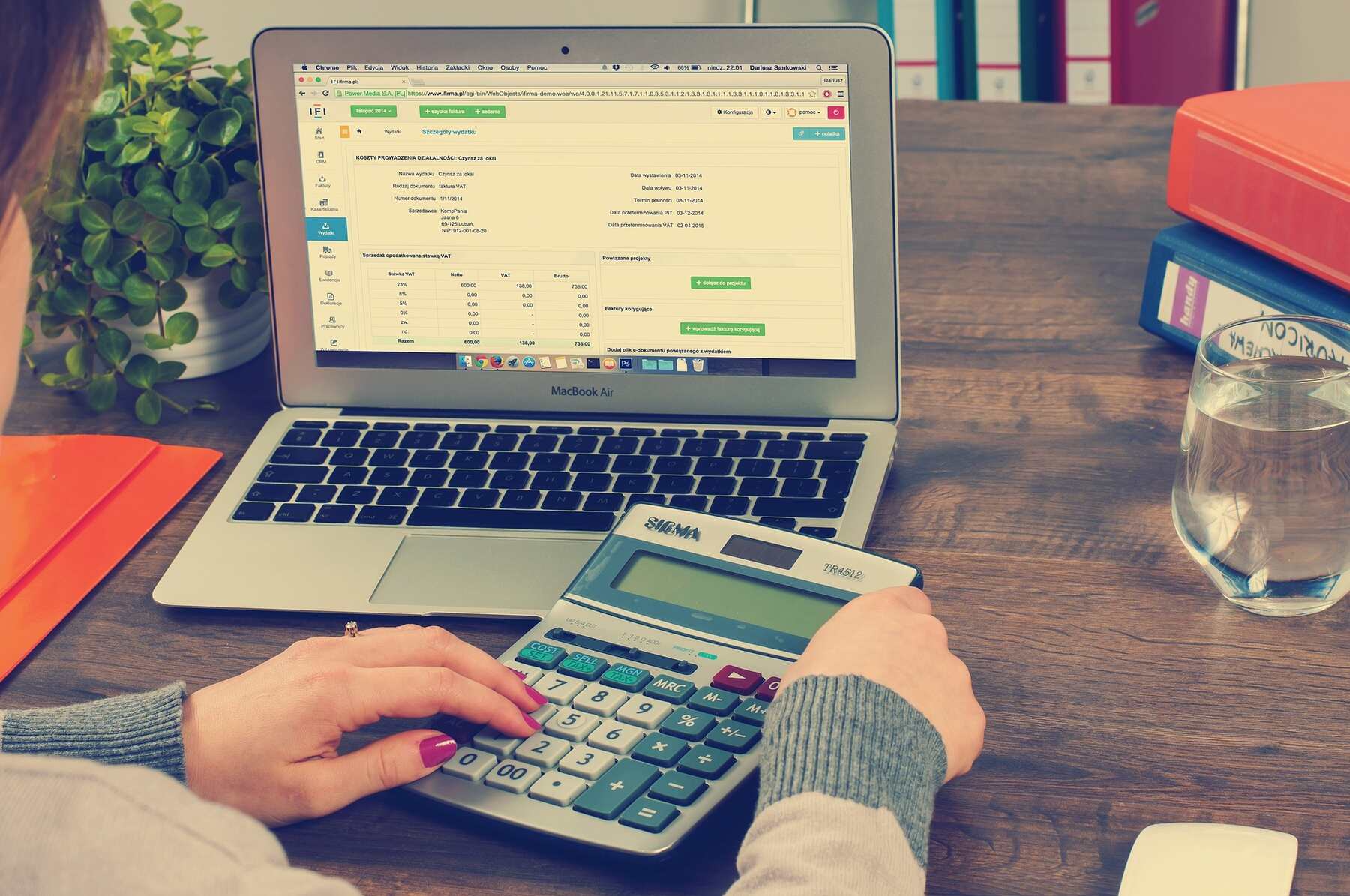 A woman using a spreadsheet on a laptop and calculator to manage their business