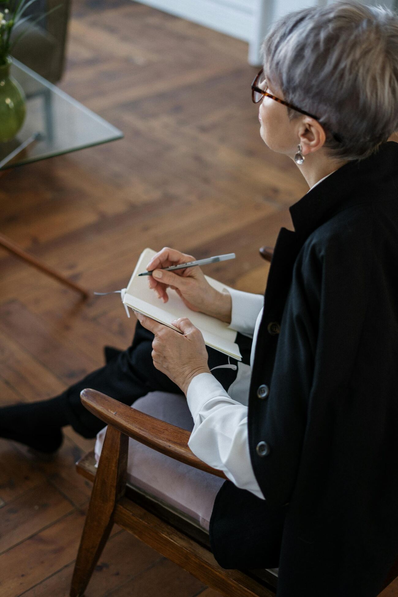 A woman sitting in a chair, focused on writing in a notebook