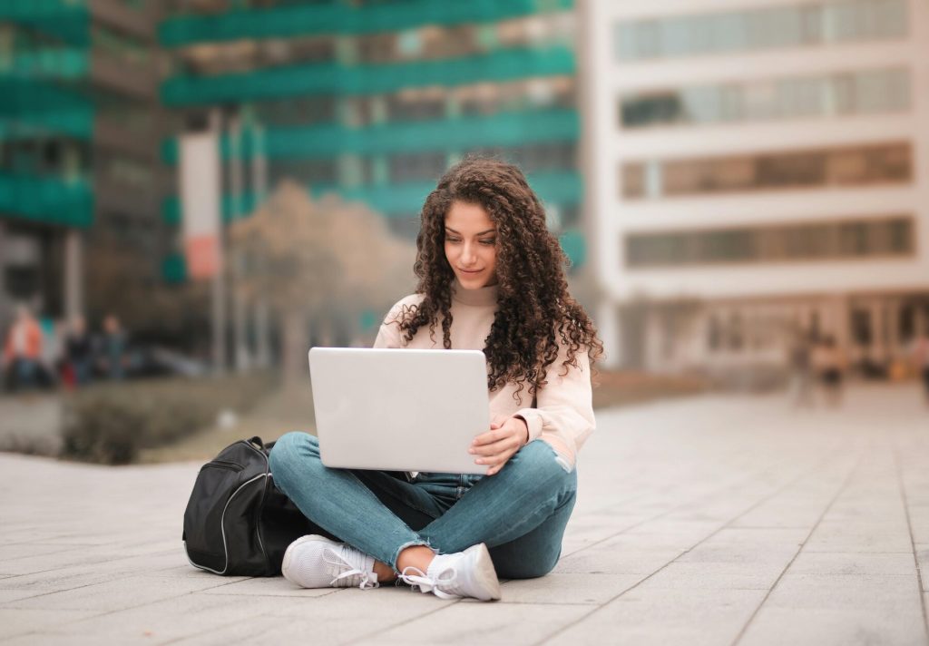 Female college student sitting on the ground with her laptop