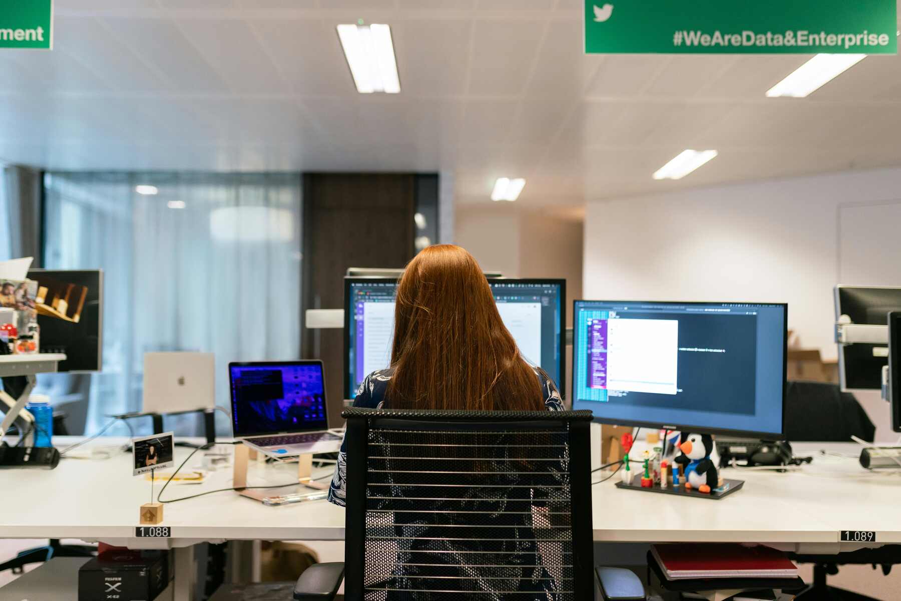 A woman using multiple monitors and devices on her work table