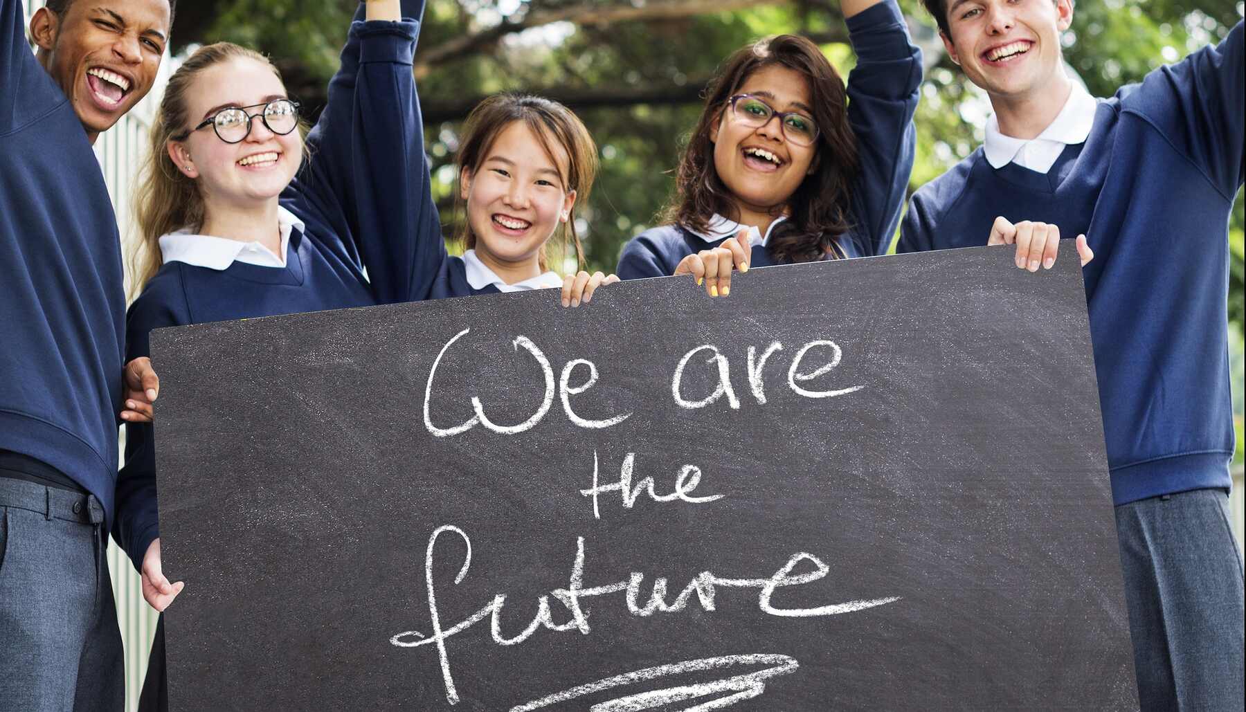 A diverse group of students proudly holding a sign that reads "We are the future"