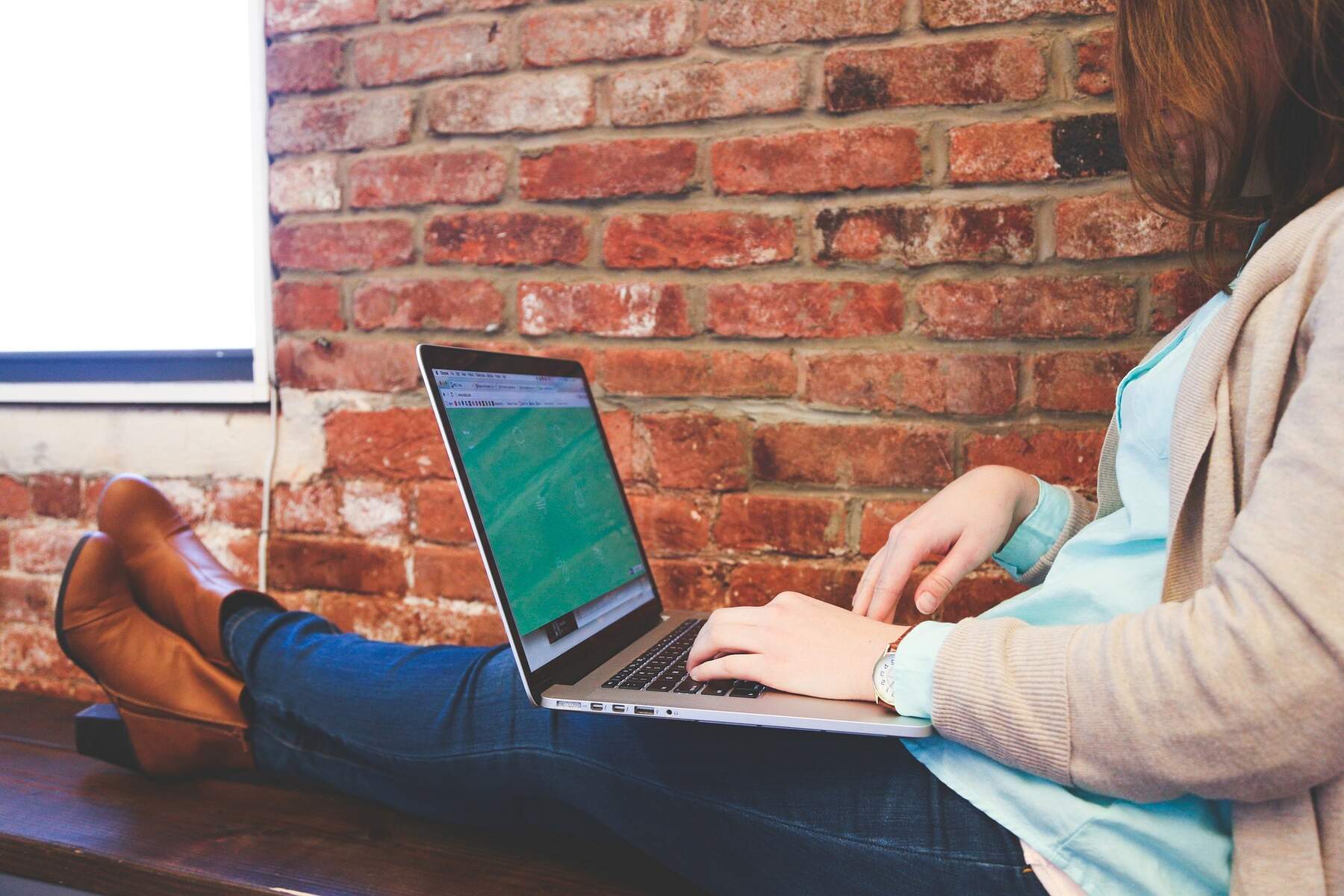 A woman sitting on a bench with her laptop, engrossed in her work outdoors