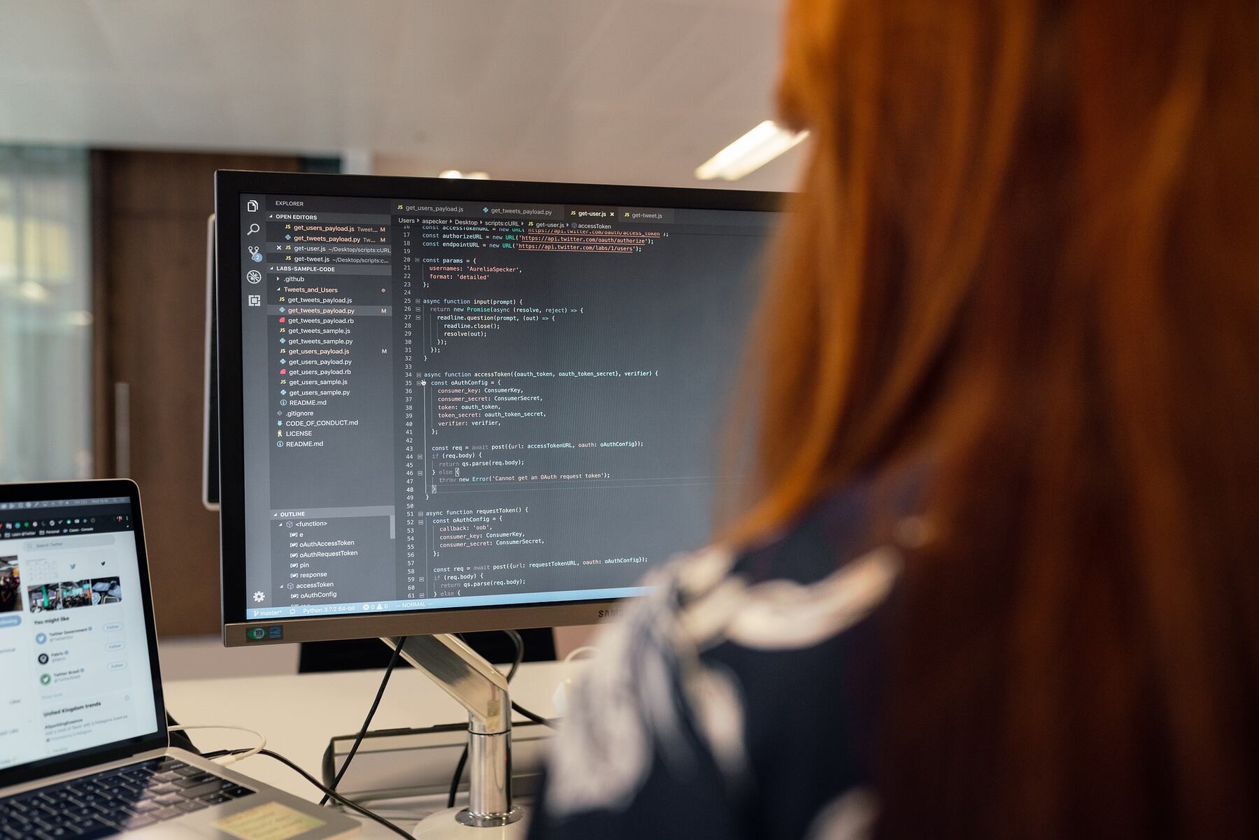 A woman intently working on a computer, focusing on the code displayed on the screen
