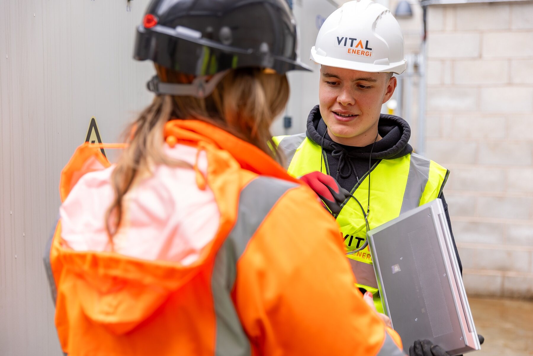 Two workers in hard hats having a conversation at a construction site
