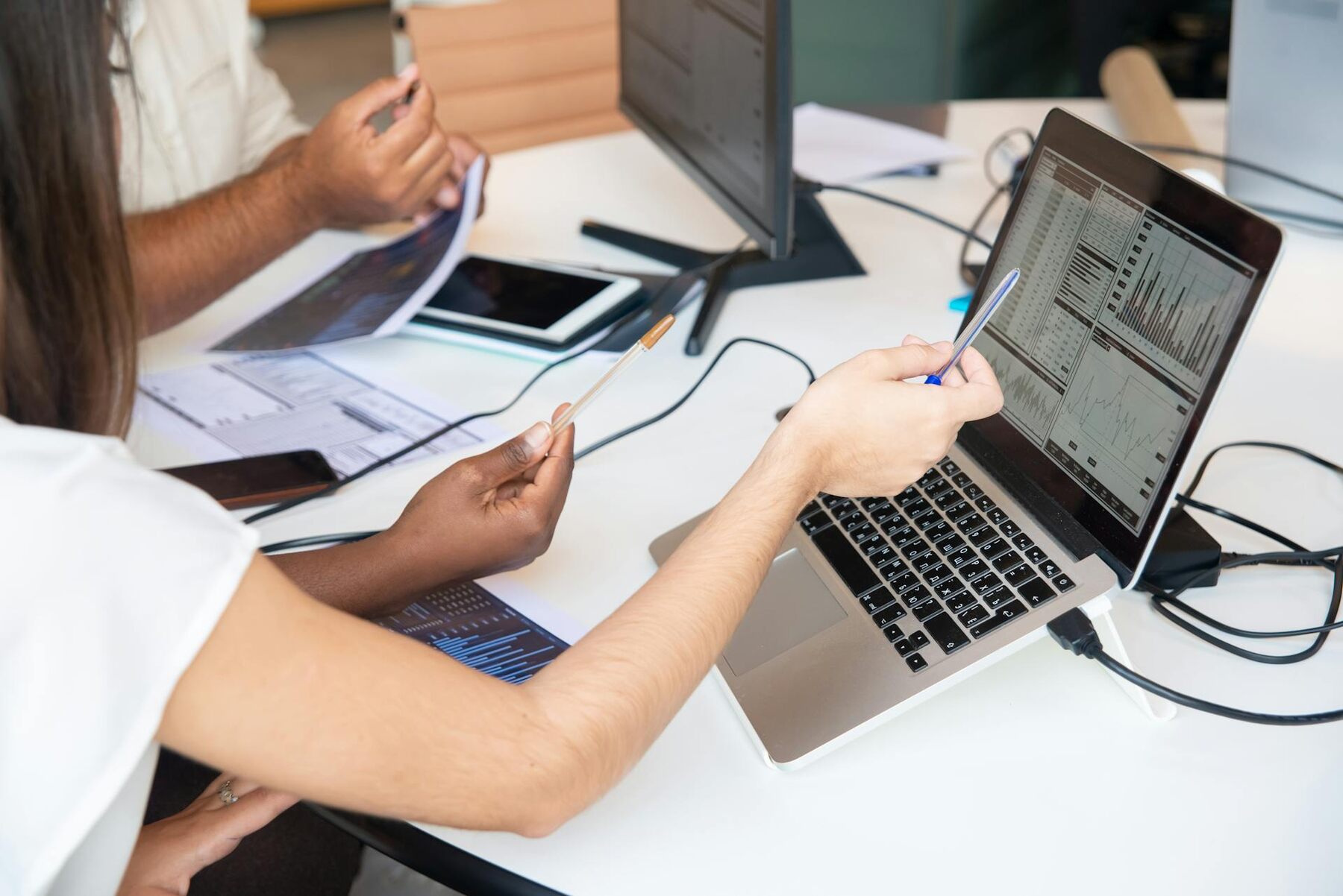 Two individuals collaborating on a laptop at a table, engrossed in their work