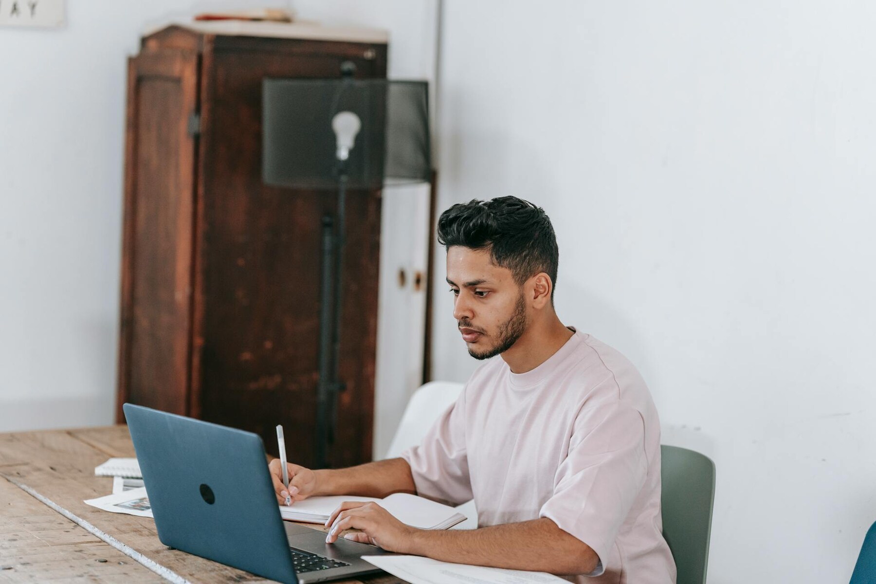 A man sitting at a table with a laptop, focused on the screen