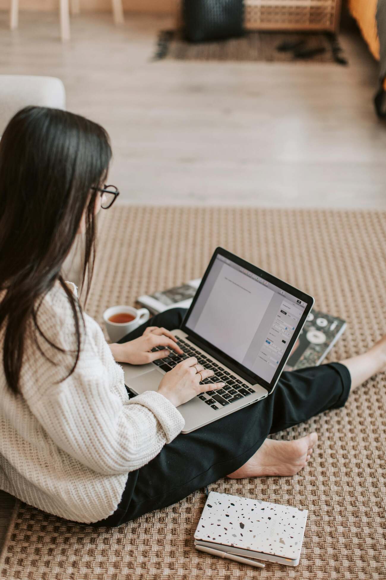 A woman sitting on the floor, focused on her laptop