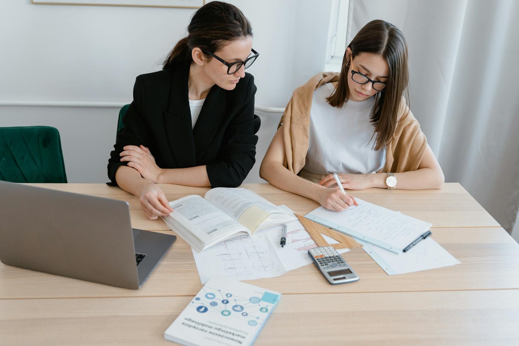 Two women collaborating at a table with a laptop and papers