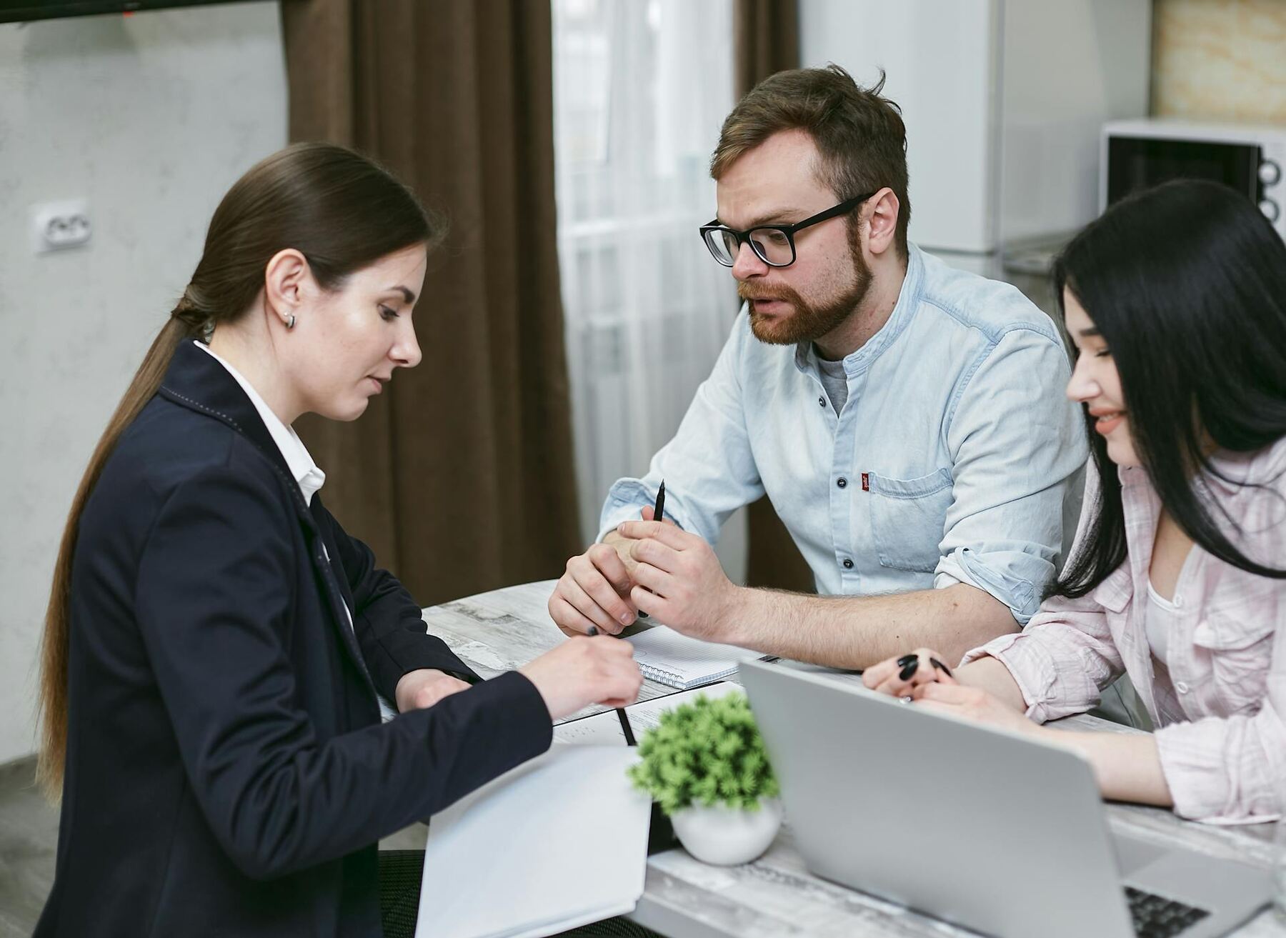 A woman in suit pointing on documents while a couple are listening to her