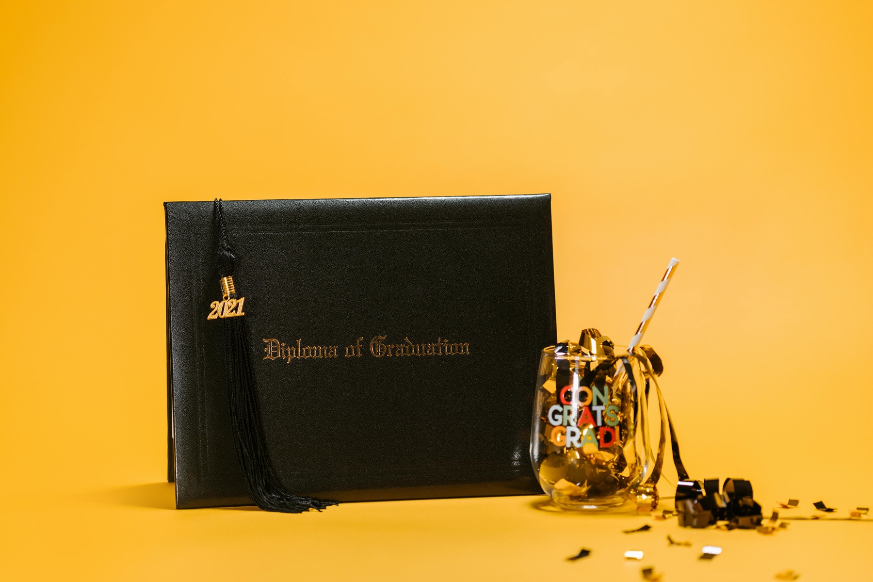 Graduation diploma next to a clear jar filled with confetti