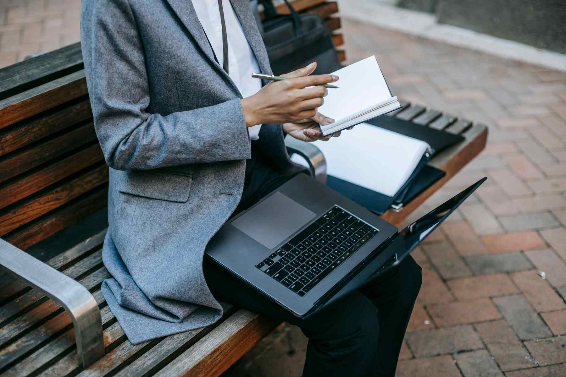 A woman writing on her notebook with her laptop open