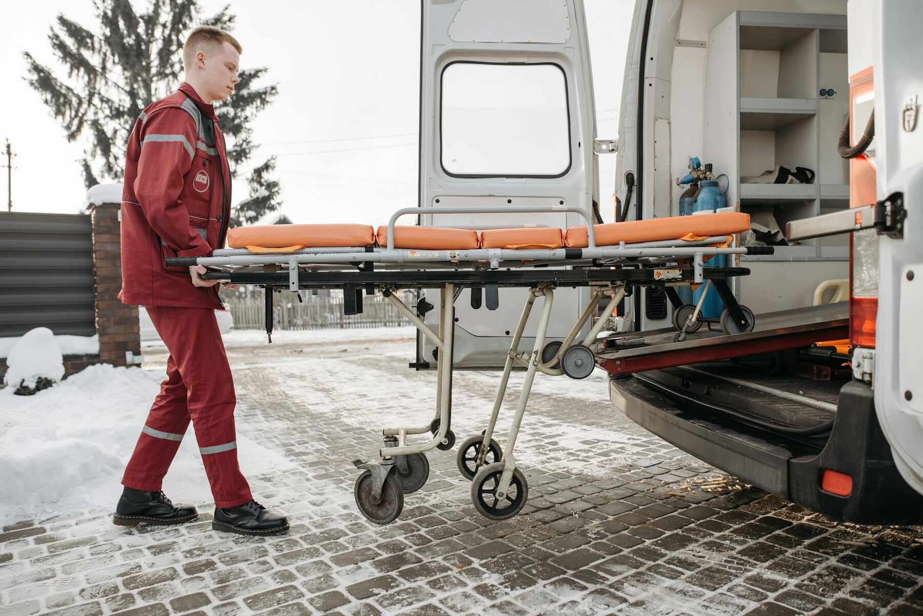 A man lifting stretcher onto vehicle